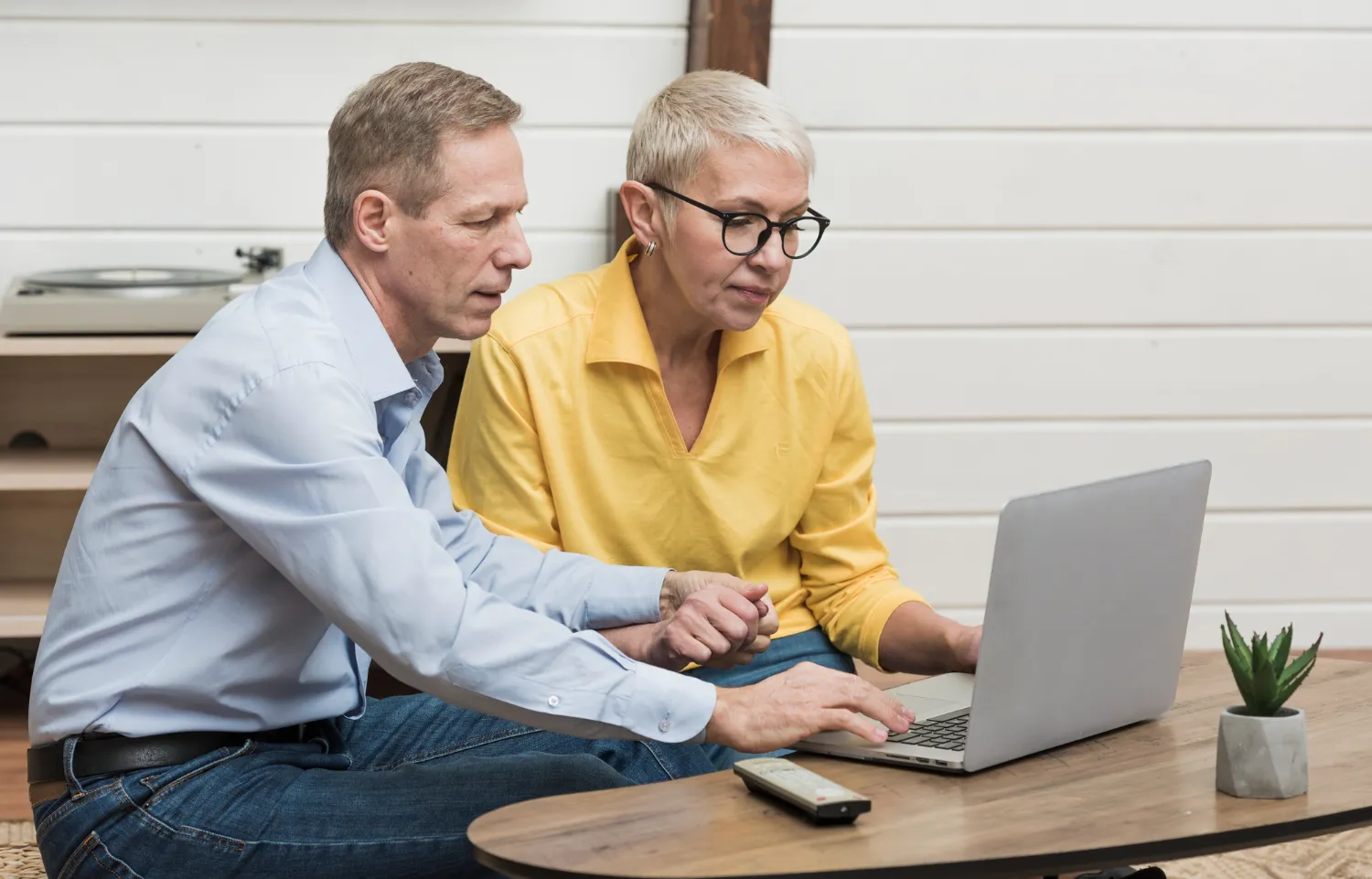 Senior man looking through his laptop next to his wife Senior man looking through his laptop next to his wife